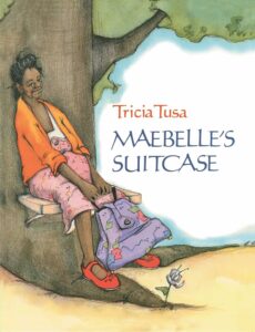 The cover of Maebelle's Suitcase, by Tricia Tusa. The picture features an African American woman sitting on a bench leaning against a tree with a fabric bag in her hand.